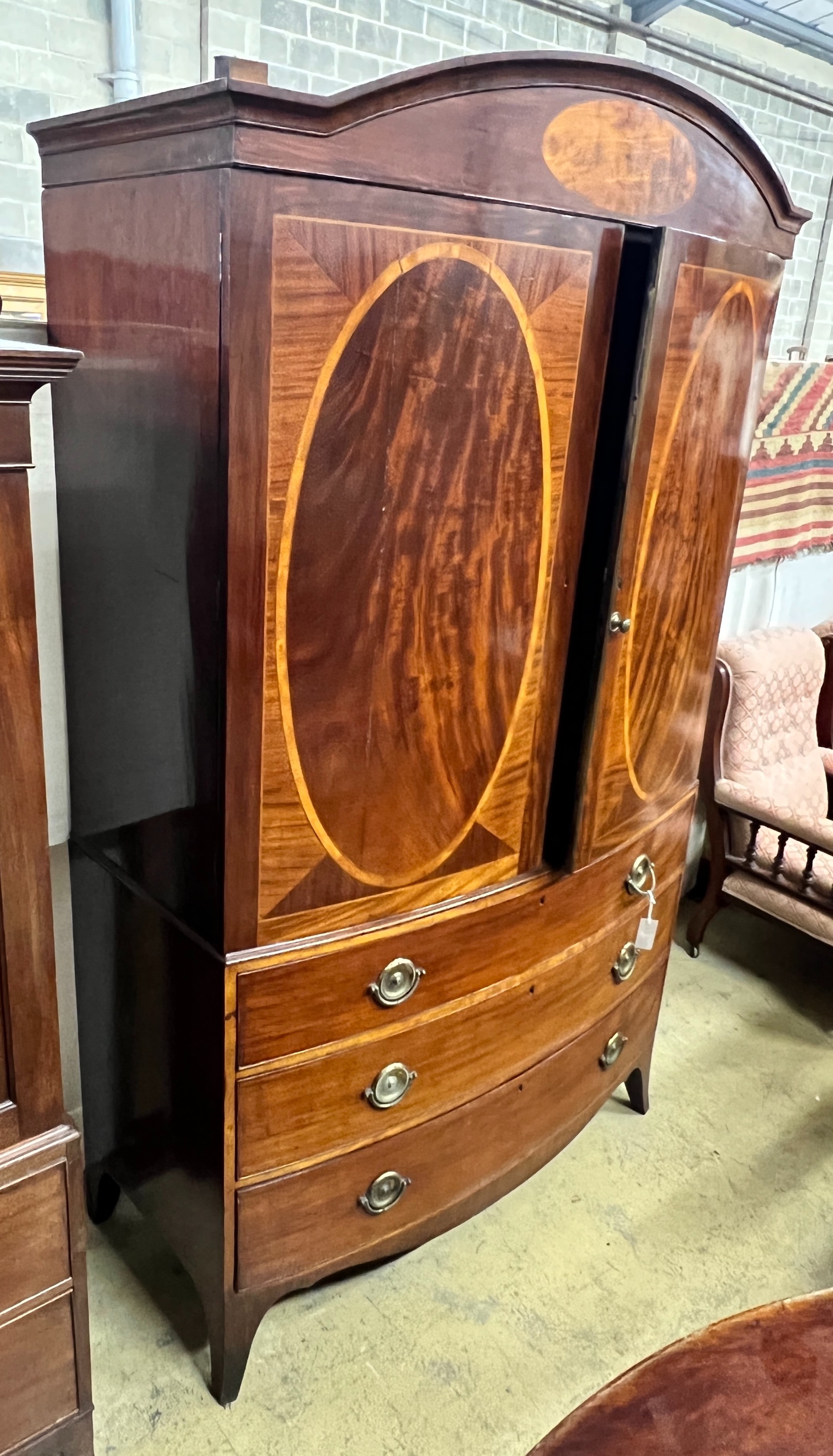 A George IV satinwood banded mahogany bow front linen press, adapted, width 130cm, depth 60cm, height 218cm